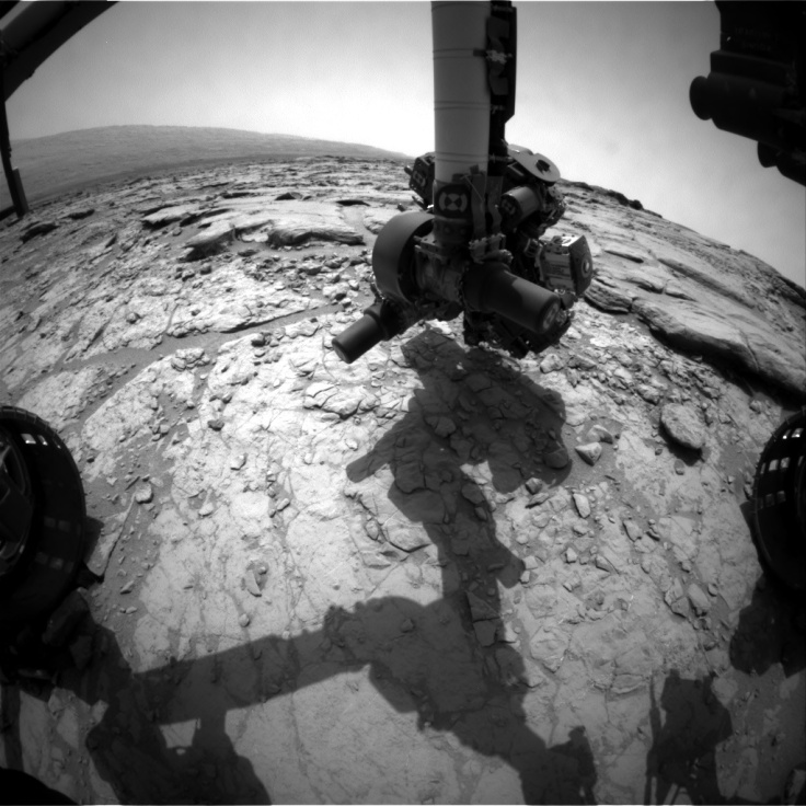 An image from the front hazard camera on Curiosity from today's location showing the instrument arm extending down to inspect the rocks in front of the rover.  Image Credit: NASA/JPL-CalTech