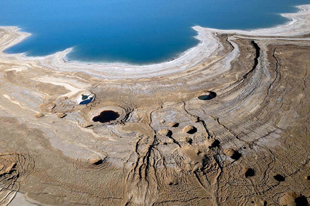 Sinkholes along the shores of the Dead Sea.  these form when layers of salt beneath the ground dissolve in groundwater creating underground caverns.